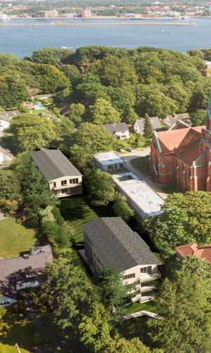 Luftaufnahme eines Wohngebiets mit einer großen roten Kirche in der Mitte, umgeben von Bäumen und mehreren Häusern