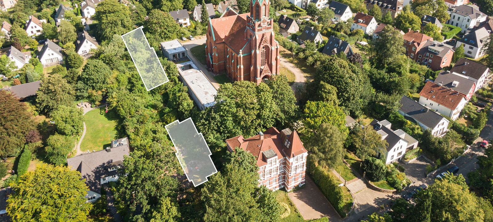 Luftaufnahme eines Wohngebiets mit einer großen roten Kirche in der Mitte, umgeben von Bäumen und mehreren Häusern