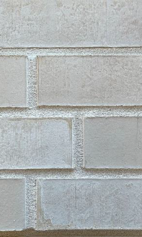 Nahaufnahme einer hellgrauen Ziegelsteinmauer mit unregelmäßiger Struktur